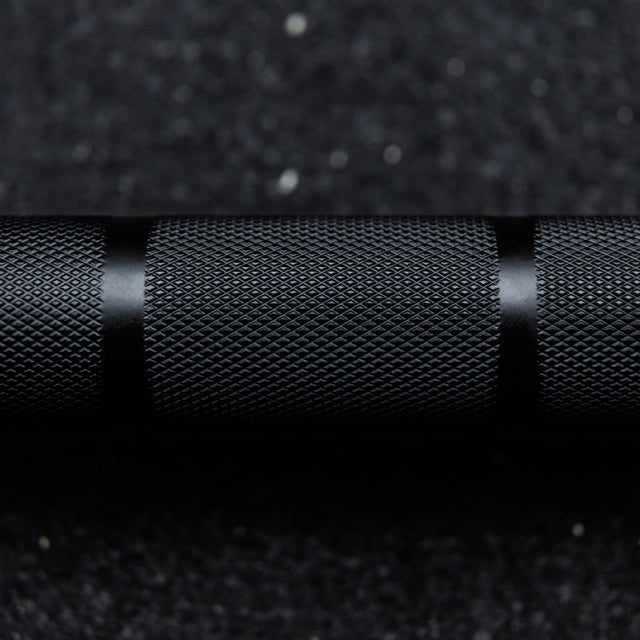 Close-up of the knurl marks and center rings on the black 20kg Hybrid Bar